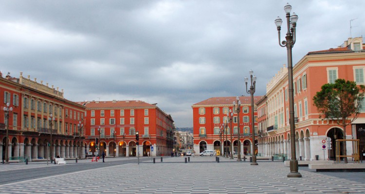 Place Massena, Nice's large square is rimmed by red ochre buildings and features a grey and black checkered pavement. Credit: Julie Kalan