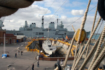 The M33 World War I warship in dry dock. The HMS Ark Royal, a decommissioned aircraft carrier in the background.