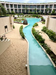 A ribbon-shaped pool flows into a cenote-inspired oasis, echoing Yucatán's underground rivers